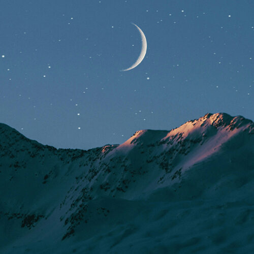Crescent mood over snowy mountains